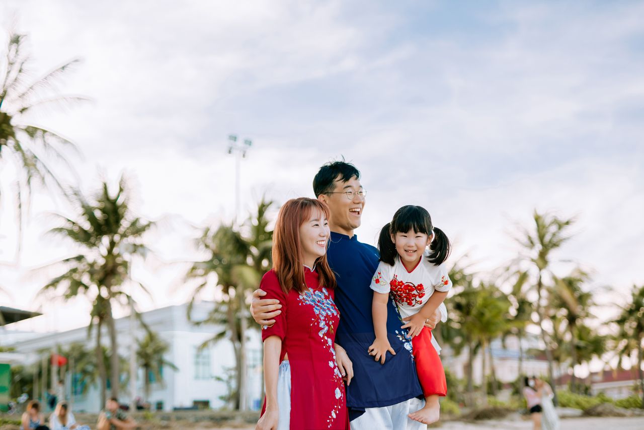 Smiling family embracing in the sunshine at a tropical beach setting.