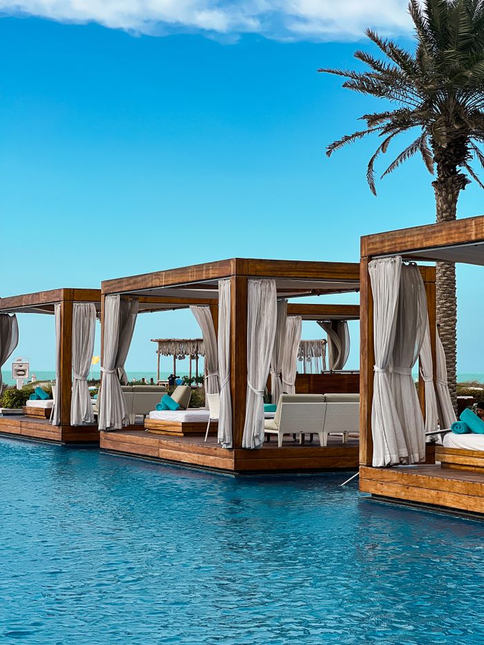 Elegant poolside cabanas under a bright sky at a luxury resort, perfect for relaxation.