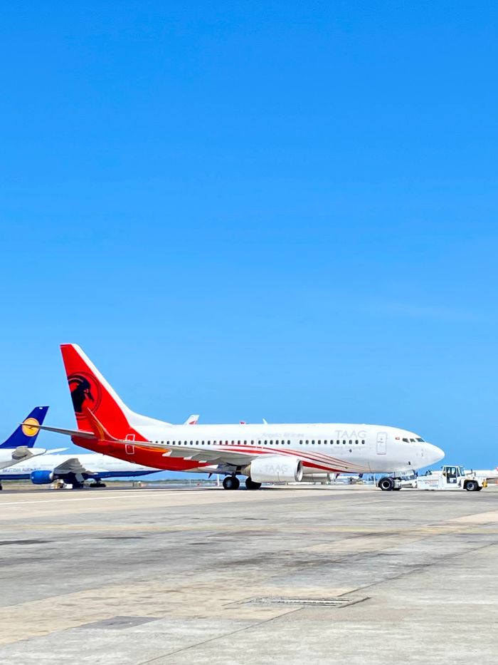 Commercial airplanes on the tarmac at Cape Town International Airport under a clear blue sky.